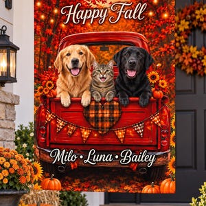 May include: A rectangular garden flag featuring a red pickup truck bed filled with a golden retriever, a tabby cat, and a black labrador. The scene includes autumn leaves, string lights, a plaid heart, and pumpkins. Text reads Happy Fall and Milo Luna Bailey.