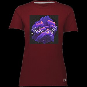 Puede incluir: Una camiseta color granate con un estampado gráfico de nubes moradas y rosas con el texto "Be Yourself" en blanco.
