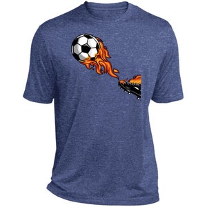 Puede incluir: Una camiseta azul con un gráfico de un balón de fútbol en llamas que es pateado por una bota.