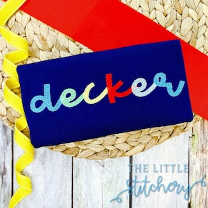 May include: A navy blue fabric with the word "decker" embroidered in rainbow colors. The fabric is on a woven straw mat.