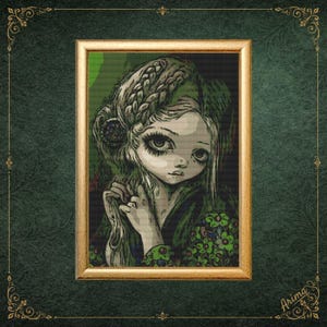 May include: A framed cross-stitch embroidery featuring a stylized portrait of a person with large eyes and braided hair. The figure wears a dark garment adorned with a green floral pattern, set against a dark background within a gold frame.