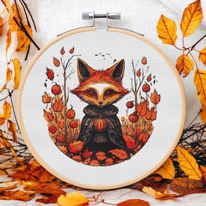 May include: A cross-stitch pattern featuring a fox wearing a cloak and holding a pumpkin. The fox is surrounded by autumn leaves and berries.