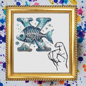 Puede incluir: Un diseño de punto de cruz enmarcado que presenta la letra X con un esqueleto de pez azul y blanco en su interior. La letra está rodeada de burbujas y algas marinas. Un signo de mano para la letra X se muestra debajo de la letra.