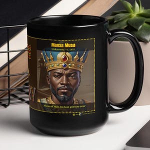 May include: Black ceramic mug with a graphic of Mansa Musa, the King of Mali, wearing a gold crown and a blue and gold robe. The text "Mansa Musa, Unknown - c. 1337, Mansa of Mali, Richest person ever" is printed on the mug.