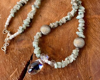 May include: A light green and white stone necklace with silver accents. The necklace features a glass pendant with blue and purple swirls.