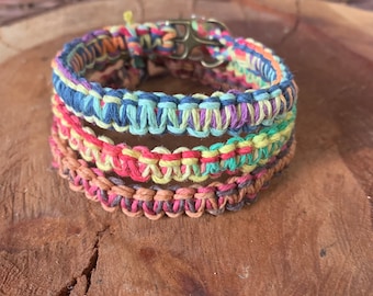 May include: Multicolored woven bracelet with a silver clasp. The bracelet is made of several strands of colorful thread, creating a layered effect.