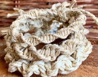 May include: Three braided hemp bracelets in a natural beige color. The bracelets are stacked on top of each other, showing the intricate knotting pattern.