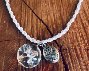 May include: White braided cord necklace with a silver charm that says "follow your dreams" and a glass pendant with a dandelion inside.