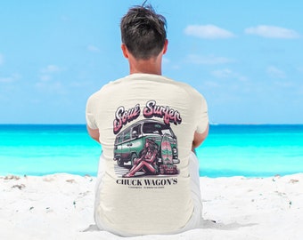 May include: A white t-shirt with a green vintage van and a woman sitting on the back with a surfboard. The text on the shirt says "Soul Surfer" and "Chuck Wagon's California Summer Vacation."