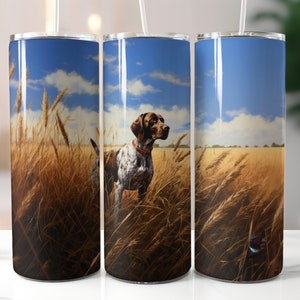 May include: Three stainless steel tumblers with a design of a brown and white hunting dog standing in a field of tall grass. The background is a blue sky with white clouds.