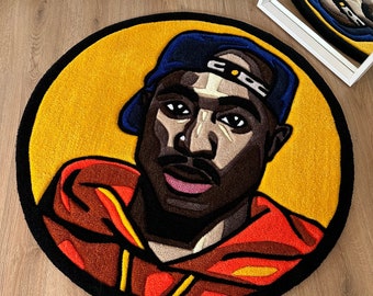 May include: A round rug with a black border features a cartoon portrait of a person wearing a blue baseball cap and a red hoodie. The background is yellow.