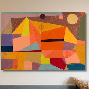 May include: Abstract geometric art print with a colorful design featuring shades of orange, yellow, red, blue, green, and purple. The print is framed and hanging on a wall above a gray couch.
