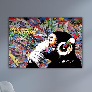 May include: A colorful graffiti art print featuring a chimpanzee wearing headphones. The artwork includes the text "WHEN WORDS FAIL MUSIC SPEAKS" and a vibrant background of graffiti tags in various colors.