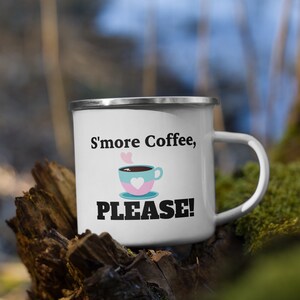Może przedstawiać: Biały emaliowany kubek do campingu z czarno-białym nadrukiem z napisem "S'more Coffee, PLEASE!" i kreskówkowym obrazkiem filiżanki kawy z sercowatą chmurką pary.
