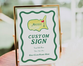 Puede incluir: Un letrero personalizado en un marco dorado. Presenta un diseño de mapa verde y amarillo con la palabra "Masters" y una bandera roja. El letrero también incluye las palabras "Custom Sign" y espacio para información personalizada.