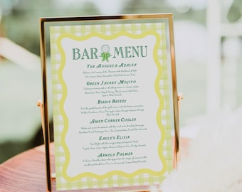 Pode incluir: Um menu de bar com moldura dourada e fundo xadrez verde e branco. O menu lista bebidas com nomes relacionados ao golfe, como "The Augusta Azalea", "Green Jacket Mojito" e "Birdie Breeze".