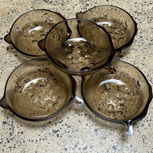 May include: Set of five brown glass bowls with a textured bubble design. The bowls have a rounded shape with a small handle on each side.