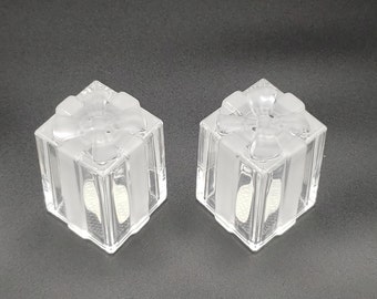 May include: A pair of clear glass salt and pepper shakers shaped like gift boxes with a bow on top.