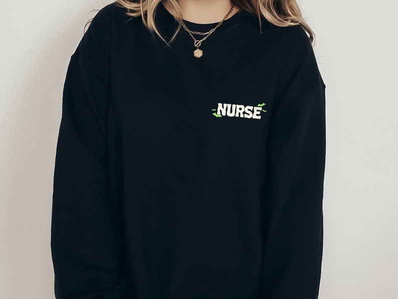 May include: Black sweatshirt with a green and white embroidered design that says "NURSE".