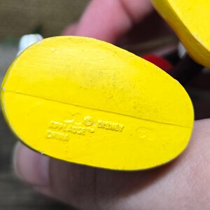 May include: Yellow plastic bottom of a toy figure with the text "Applause" and "Disney" and "China" printed on it.