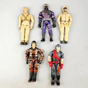 May include: Five plastic action figures arranged in two rows. The top row features three figures in tan, purple, and tan uniforms. The bottom row includes a brown figure with silver accents and a black figure with red details and the word COBRA.