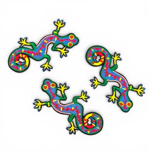 May include: Three embroidered lizard patches. Each lizard has a blue body with a red and yellow pattern, green legs and tail, and yellow feet. The lizards are on a white background.