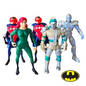 May include: A collection of five action figures including a character in a green suit, two figures in blue and red armour, a figure in gold and silver armour with a scarf, and a silver armoured figure, accompanied by a yellow and black bat logo.