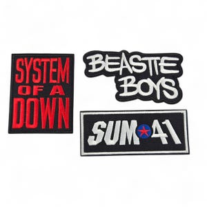 Peut inclure: Trois écussons brodés avec des logos de groupes. L'un d'eux affiche "SYSTEM OF A DOWN" en rouge sur un rectangle noir. Un autre dit "BEASTIE BOYS" en blanc sur une forme noire incurvée. Le troisième affiche "SUM 41" en blanc sur un rectangle noir.