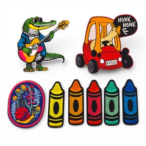 Peut inclure: Ensemble de patchs brodés représentant un alligator de dessin animé jouant de la guitare, un chien conduisant une voiture rouge, un escargot dans un jardin et cinq crayons colorés. Les patchs sont de formes et de tailles variées.
