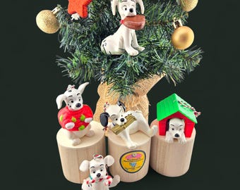 May include: Christmas tree decorated with Dalmatian-themed ornaments. The ornaments include figurines of the dogs in various poses, some holding objects. The tree also has red star ornaments and gold baubles.