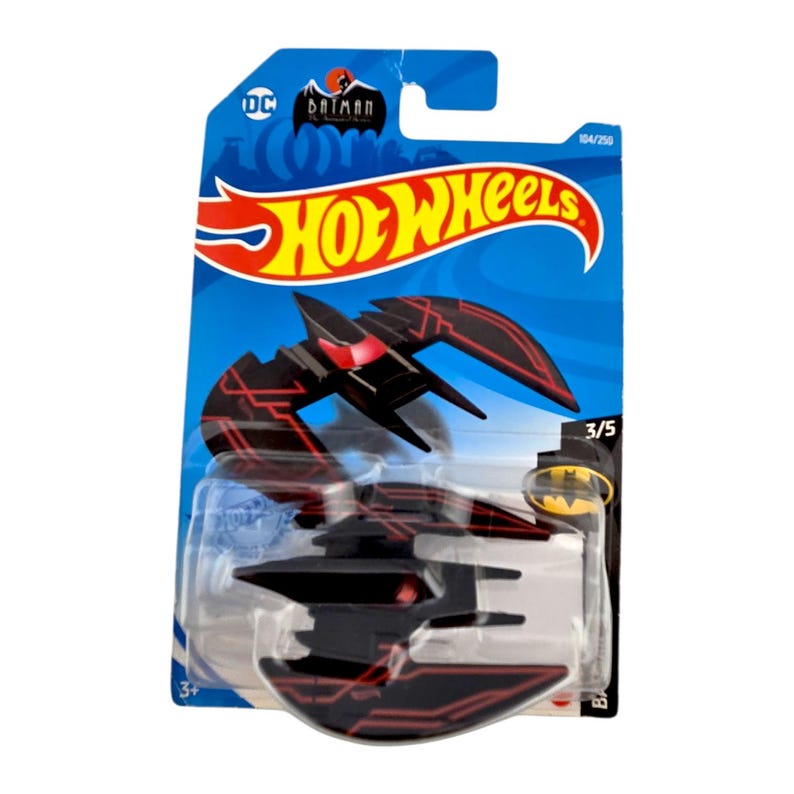 K&ouml;nnte beinhalten: Ein schwarzes und rotes Hot Wheels Spielzeugauto in Form eines fledermausartigen Flugzeugs. Das Spielzeug befindet sich auf einer blau-wei&szlig;en Karte mit dem Batman-Logo und dem Hot Wheels-Logo. Die Karte zeigt "104/250" und "3/5".