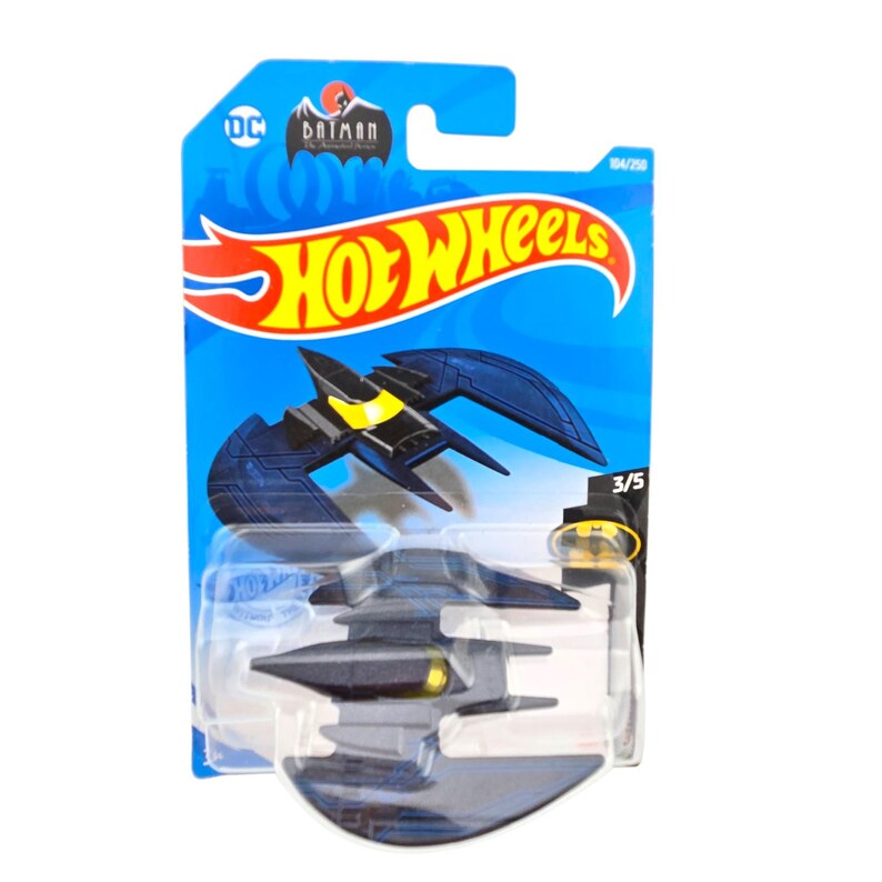 K&ouml;nnte beinhalten: Ein Hot Wheels Spielzeugauto des Batwing aus der Batman-Zeichentrickserie. Das dunkelblaue Fahrzeug hat gelbe Akzente und ist auf einer blauen Karte mit den Hot Wheels- und DC Batman-Logos verpackt.