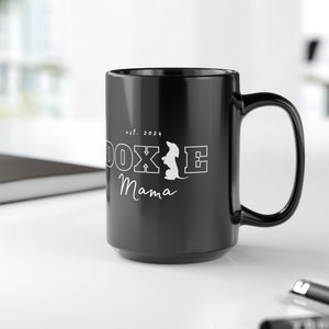 Black Doxie Mama mug with white lettering on a clean office desk.