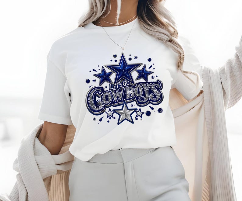 以下が含まれることがあります： 星と「Let's Go Cowboys」の文字が書かれた、青と銀のグラフィックが施された白いTシャツです。