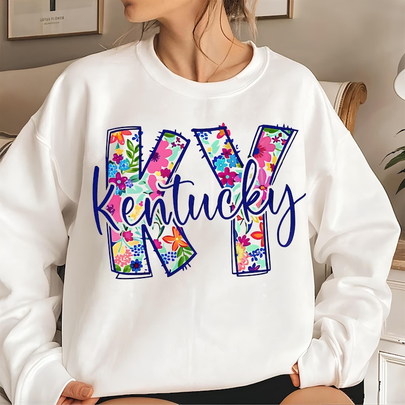 May include: White sweatshirt with a floral design of the letters KY and the word "Kentucky" in blue lettering.
