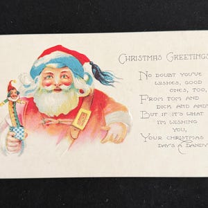 May include: A vintage Christmas postcard featuring an illustration of Santa Claus wearing a red and blue hat, holding a small toy in a box. The text reads: Christmas Greetings, No doubt you've wishes, good ones, too, From Tom and Dick and Andy, But if it's what I'm wishing you, Your Christmas day's a dandy.