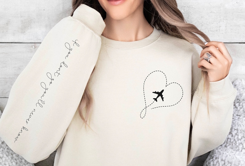 May include: A cream-colored sweatshirt with a black airplane flying through a heart shape on the front. The left sleeve has the text "If you want to go, you will find a way" written in cursive.