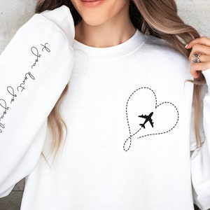 May include: White sweatshirt with a black airplane flying through a dotted line heart on the front. The left sleeve has the text "You will travel far" written in cursive.