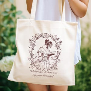 May include: A white tote bag with a brown illustration of a woman reading a book. The illustration is surrounded by a floral design. The text "I declare after all, there is no enjoyment like reading" is printed below the illustration.