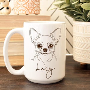 May include: White ceramic mug featuring a line drawing of a Chihuahua's face. The dog's name, "Lucy," is written in cursive below the image. The mug has a large handle and is suitable for hot or cold beverages.