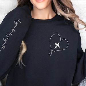May include: Black sweatshirt with a white airplane flying inside a heart shape on the front. The text "Follow your own compass" is written on the left sleeve.