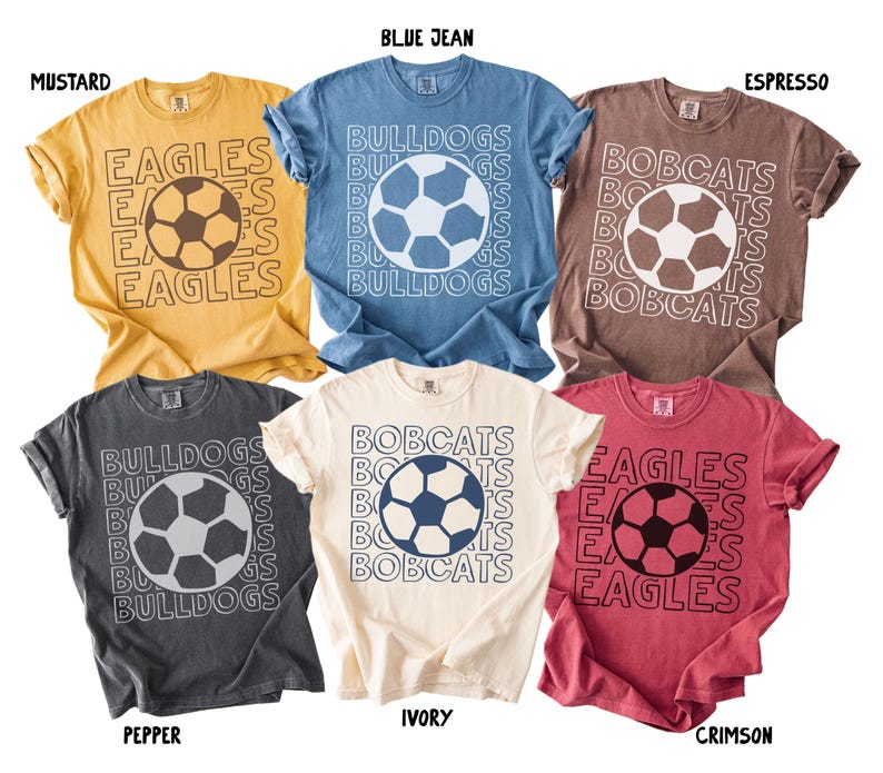 K&ouml;nnte beinhalten: Sechs kurz&auml;rmelige T-Shirts in den Farben Senf, Jeansblau, Espresso, Pfeffer, Elfenbein und Karmesinrot. Jedes T-Shirt zeigt eine zentrale Fu&szlig;ballgrafik, umgeben von wiederholten Teamnamen wie Eagles, Bulldogs und Bobcats in wei&szlig;er oder schwarzer Umriss-Schrift.