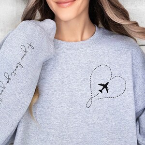 May include: Gray sweatshirt with a heart-shaped airplane design and the text "Forever Young, Forever Free" on the sleeve.