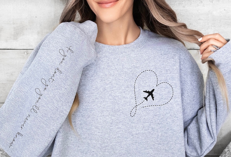 May include: Gray sweatshirt with a heart-shaped airplane design and the text "Forever Young, Forever Free" on the sleeve.