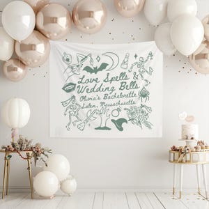 May include: A white fabric banner with green illustrations and text that reads "Love Spells & Wedding Bells, Olivia's Bachelorette, Salem, Massachusetts." The banner is decorated with images of a bat, lips, a witch's hat, and a skeleton. Balloons in white and rose gold are in the background.