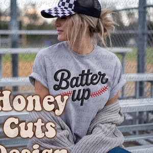 May include: A gray t-shirt with the text "Batter Up" and a baseball graphic. The image also features a black and white checkered baseball cap. The words "Honey Cuts Design" are also visible.