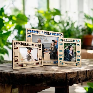 May include: Three wooden picture frames with a graduation theme. Each frame has a different photo of a graduate in a cap and gown. The frames are decorated with graduation caps, diplomas, and gowns. The text "Graduate" is printed on each frame.