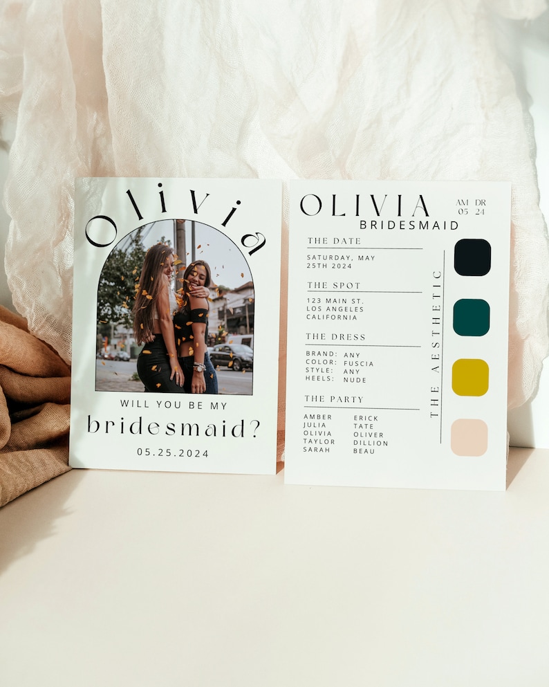 以下が含まれることがあります： 「Olivia Bridesmaid」と黒文字で書かれた白いカードで、背景には2人の女性の画像があります。カードには、日付、場所、ドレス、パーティーに関する情報も記載されています。