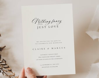 May include: A cream-coloured wedding invitation with black script that reads "Nothing fancy, JUST LOVE." The invitation includes the names Claire & Marcus, and the date, time, and location of the wedding. The invitation is held by a hand.