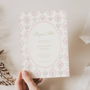 May include: A baby shower invitation with a pink and white floral design. The invitation includes the text "Bonjour Bébé" and details for Elizabeth Thomas's baby shower, including the date, time, and location.